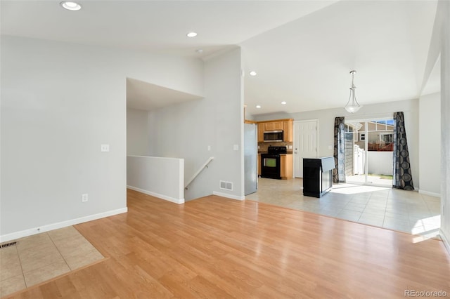 unfurnished living room with light wood-type flooring and vaulted ceiling