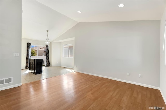 unfurnished living room featuring a notable chandelier, vaulted ceiling, and light hardwood / wood-style flooring