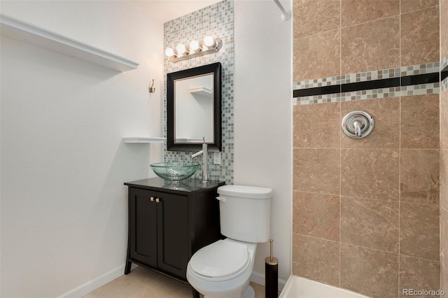 bathroom featuring a tile shower, vanity, and toilet