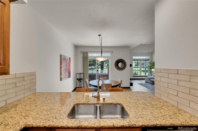 2972 W Long Dr Unit C, Littleton, CO 80120 - kitchen with backsplash, light stone counters, decorative light fixtures, a textured ceiling, and open floor plan