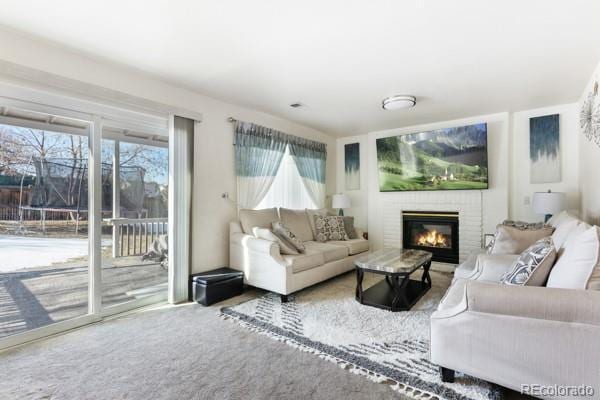 living room featuring carpet and a brick fireplace