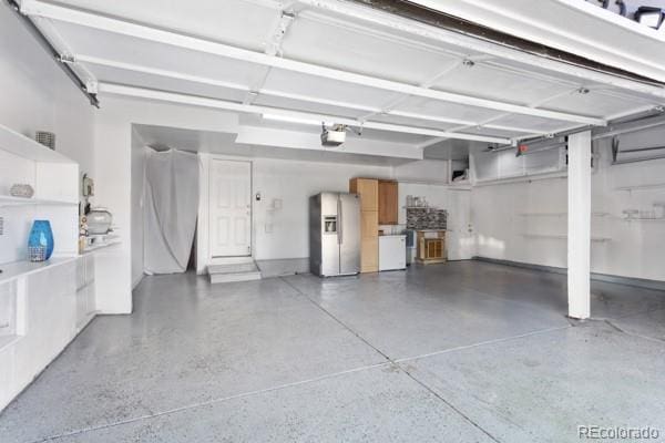 garage with a garage door opener and stainless steel fridge