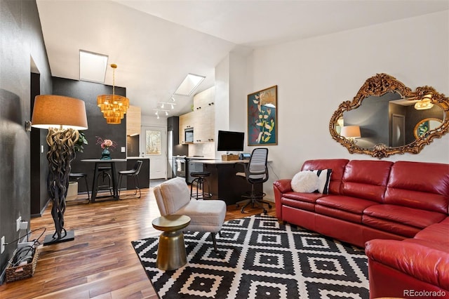 living area featuring wood finished floors, a chandelier, and vaulted ceiling