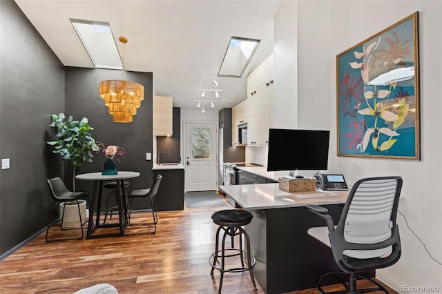 office area featuring a sink, a skylight, and wood finished floors