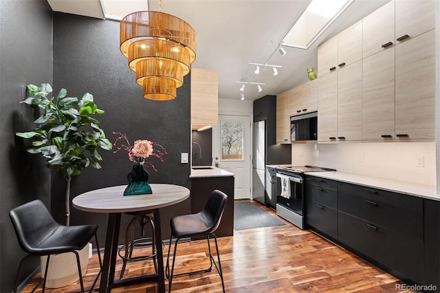 kitchen with modern cabinets, appliances with stainless steel finishes, light wood-style flooring, and a sink