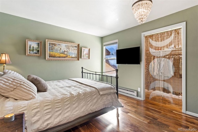 bedroom with a notable chandelier, a baseboard heating unit, baseboards, and wood finished floors