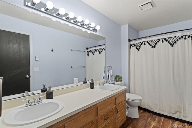 bathroom featuring double vanity, toilet, wood finished floors, and a sink