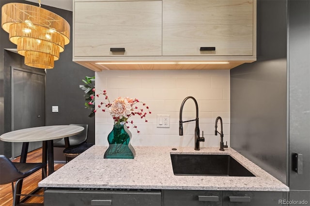 kitchen with a sink, decorative backsplash, light stone countertops, and dishwasher