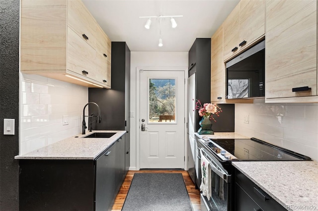 kitchen with a sink, light brown cabinets, light stone countertops, and stainless steel appliances