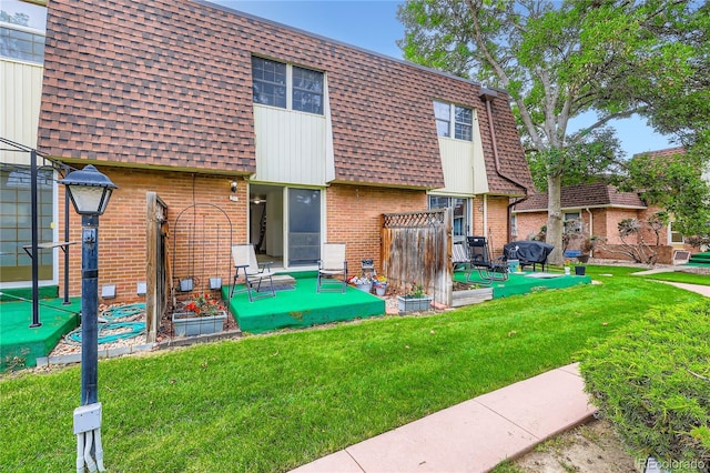1200 S Monaco St Parkway Unit 31, Denver, CO 80224 - back of house featuring brick siding, mansard roof, a shingled roof, a patio, and a yard