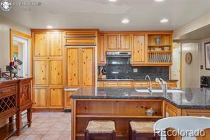 6100 Waterbarrel Rd, Beulah, CO 81023 - kitchen with open shelves, under cabinet range hood, backsplash, recessed lighting, and light tile patterned floors