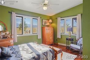 6100 Waterbarrel Rd, Beulah, CO 81023 - bedroom featuring multiple windows, lofted ceiling, wood finished floors, and baseboards
