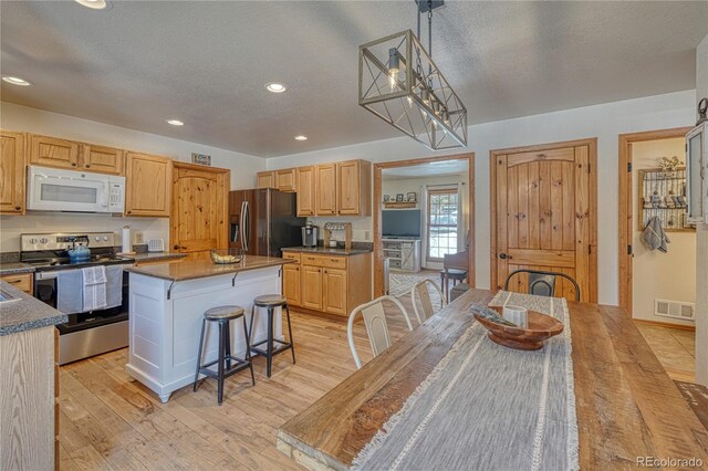 kitchen with visible vents, a center island, appliances with stainless steel finishes, a breakfast bar area, and light wood finished floors