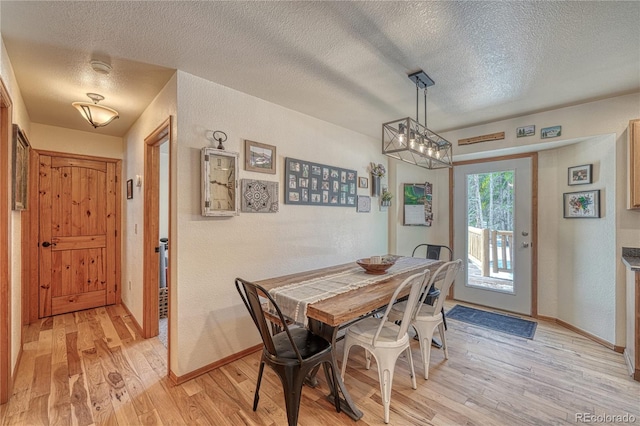 dining space with light wood-type flooring, baseboards, a textured ceiling, and a textured wall