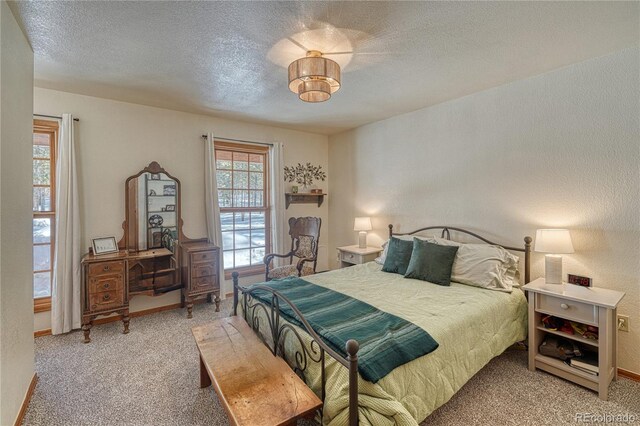 carpeted bedroom with multiple windows, a textured ceiling, and a textured wall