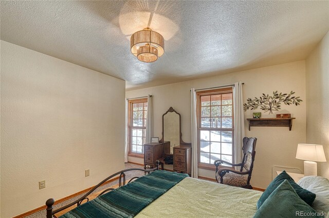 bedroom with multiple windows, a textured wall, baseboards, and a textured ceiling