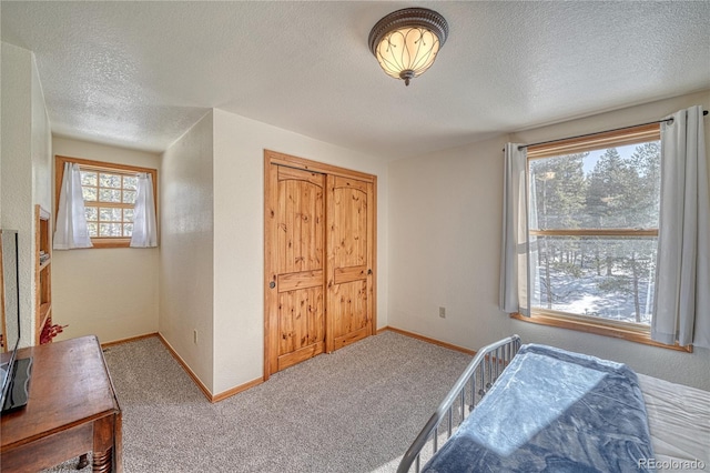 bedroom with baseboards, carpet floors, and a textured ceiling