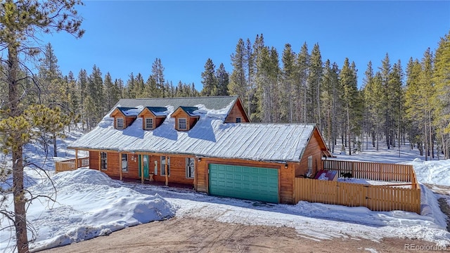 rustic home with an attached garage, fence, and a forest view