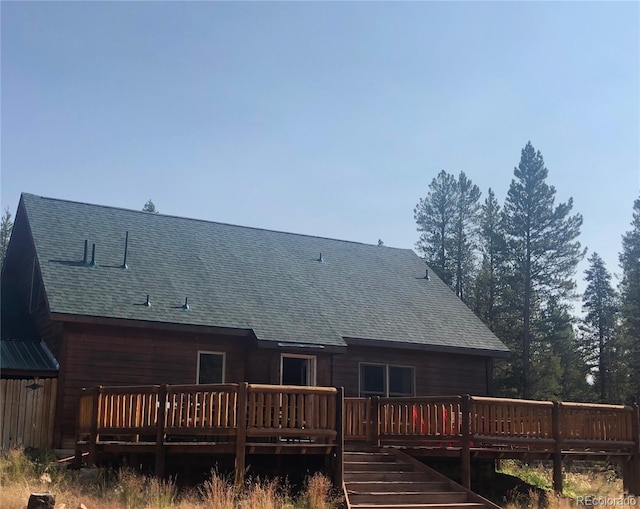 rear view of property with a wooden deck and roof with shingles