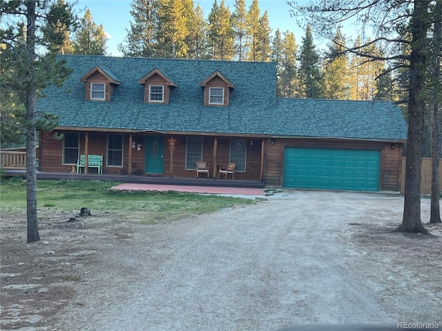 view of front facade with a porch, a garage, driveway, and roof with shingles