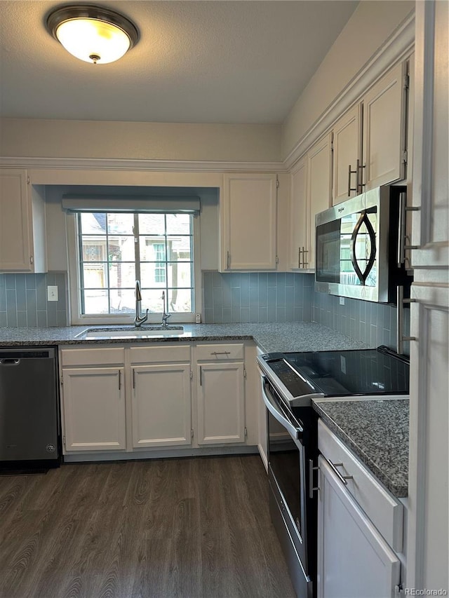 kitchen featuring appliances with stainless steel finishes, stone countertops, dark hardwood / wood-style floors, sink, and white cabinets