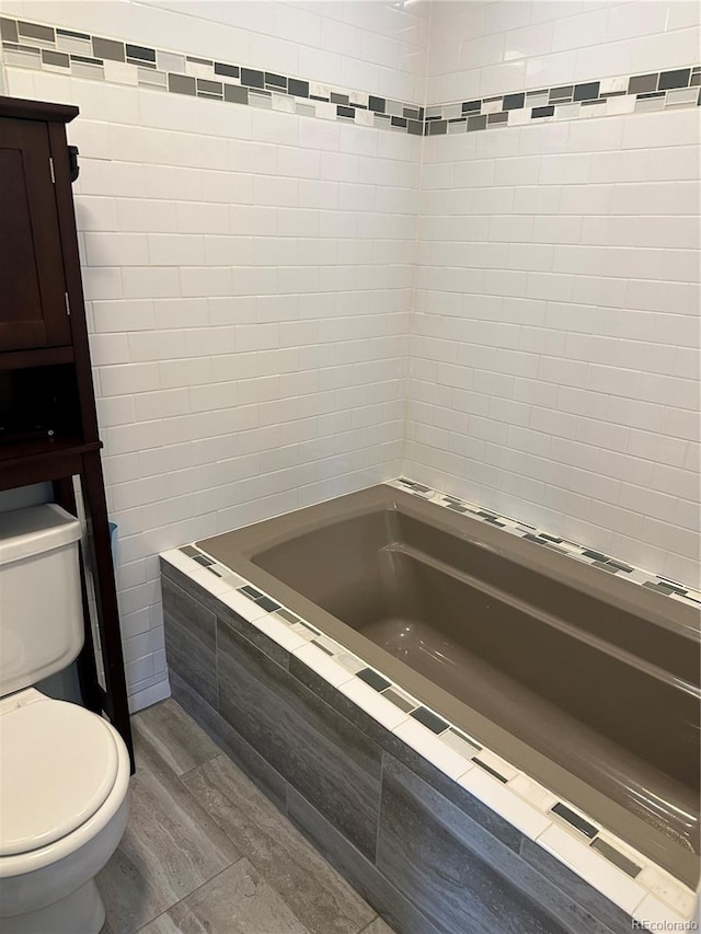 bathroom with toilet and tiled bath