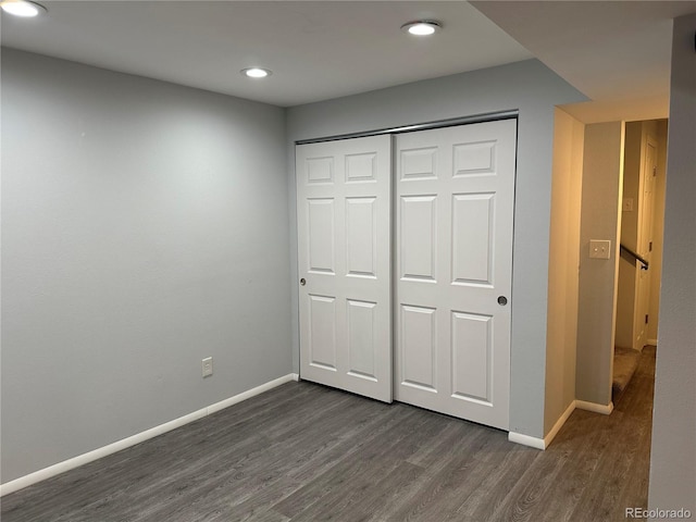 unfurnished bedroom with dark hardwood / wood-style floors and a closet