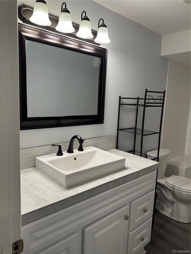 bathroom with hardwood / wood-style flooring, vanity, and toilet