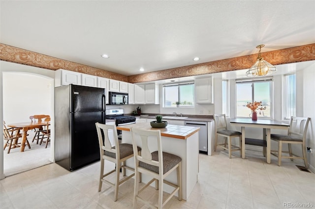 16275 Electra St, Brighton, CO 80603 - kitchen featuring a center island, a sink, white cabinets, black appliances, and tile counters