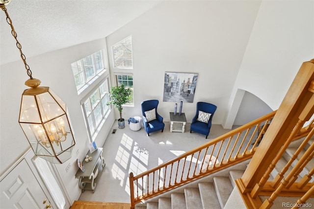 16275 Electra St, Brighton, CO 80603 - staircase with carpet flooring, a textured ceiling, a high ceiling, and a notable chandelier