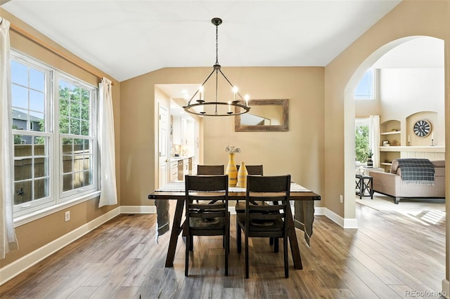 4253 Lark Sparrow St, Highlands Ranch, CO 80126 - dining area with a chandelier, wood finished floors, arched walkways, and vaulted ceiling