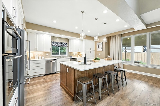 4253 Lark Sparrow St, Highlands Ranch, CO 80126 - kitchen with stainless steel dishwasher, white cabinets, a kitchen bar, light countertops, and decorative backsplash