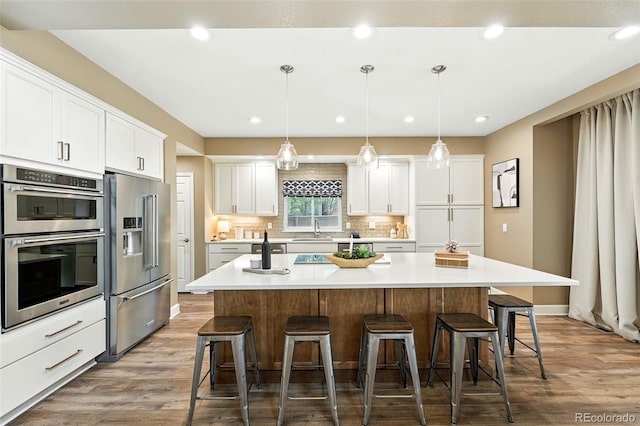 4253 Lark Sparrow St, Highlands Ranch, CO 80126 - kitchen featuring appliances with stainless steel finishes, wood finished floors, a center island, white cabinetry, and recessed lighting