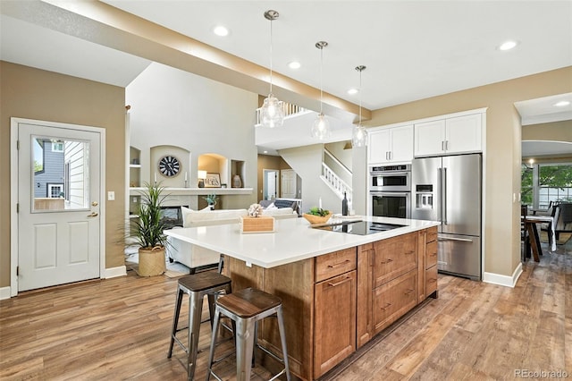 4253 Lark Sparrow St, Highlands Ranch, CO 80126 - kitchen featuring stainless steel appliances, light wood-style flooring, decorative light fixtures, a center island, and a breakfast bar area