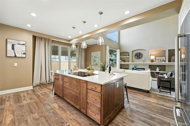 4253 Lark Sparrow St, Highlands Ranch, CO 80126 - kitchen featuring recessed lighting, a breakfast bar area, black electric cooktop, wood finished floors, and a fireplace
