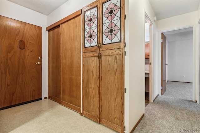 hall with light carpet and a textured ceiling