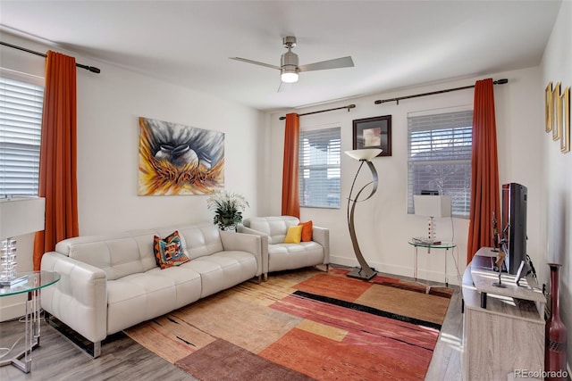 living room featuring baseboards, a ceiling fan, and wood finished floors