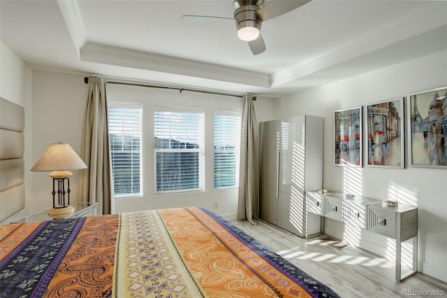 bedroom featuring a tray ceiling, wood finished floors, and ornamental molding