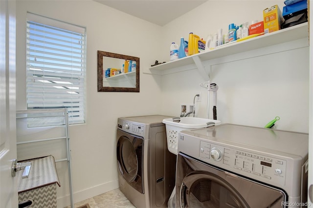 washroom with laundry area, light tile patterned flooring, washing machine and dryer, and baseboards