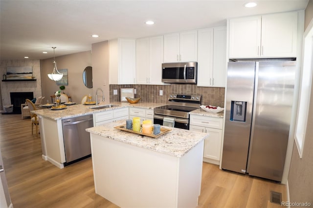 kitchen with pendant lighting, sink, white cabinets, kitchen peninsula, and stainless steel appliances