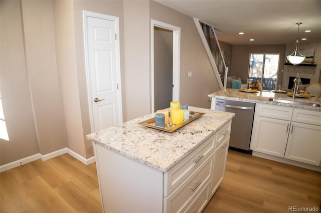 kitchen featuring white cabinetry, dishwasher, sink, a center island, and light hardwood / wood-style floors