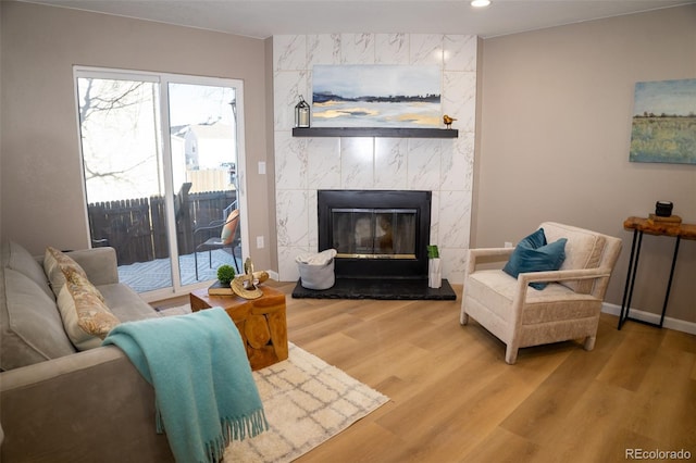 living room with a tiled fireplace and hardwood / wood-style flooring