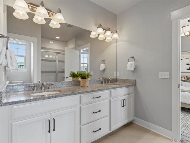 5399 Valentia St, Denver, CO 80238 - ensuite bathroom featuring baseboards, double vanity, a shower stall, and plenty of natural light