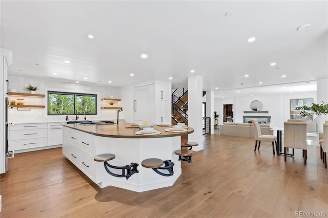 kitchen with a kitchen bar, a center island, light wood-type flooring, and white cabinetry