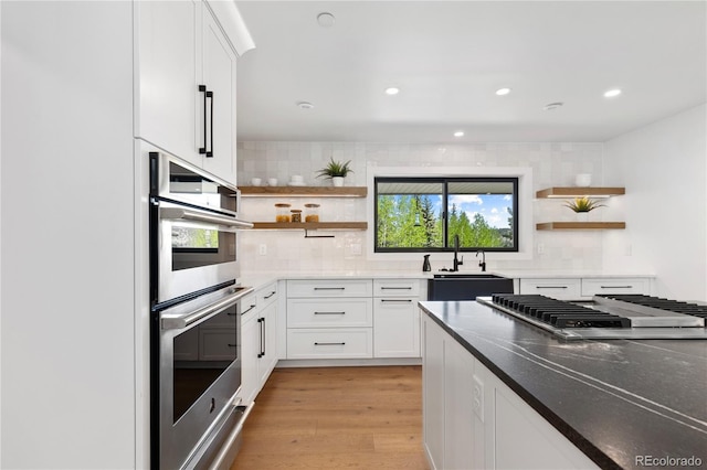 kitchen with tasteful backsplash, stainless steel appliances, sink, light hardwood / wood-style flooring, and white cabinetry