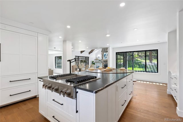 kitchen with a center island, light hardwood / wood-style flooring, white cabinetry, and stainless steel gas stovetop