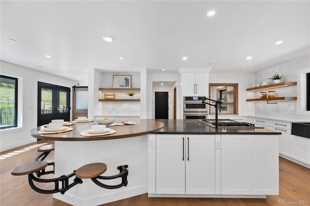 kitchen featuring white cabinets, a center island, light wood-type flooring, and appliances with stainless steel finishes