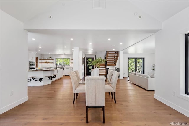 dining space featuring vaulted ceiling and light hardwood / wood-style flooring