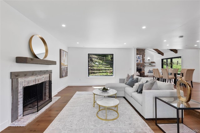 living room with hardwood / wood-style flooring, ceiling fan, and a large fireplace