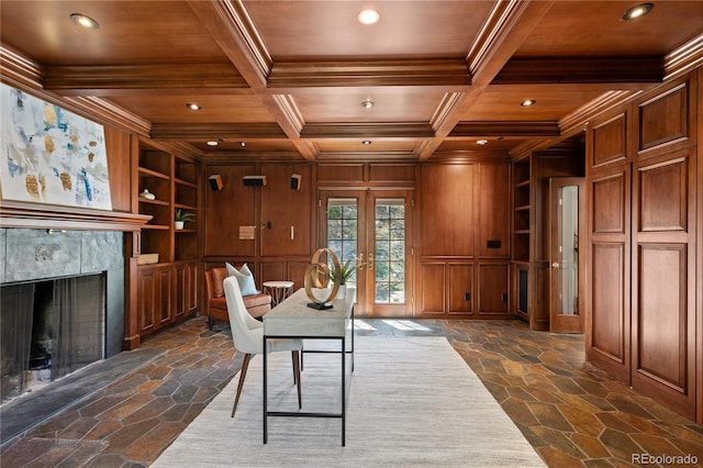 office area with beam ceiling, coffered ceiling, built in features, wood walls, and a tiled fireplace